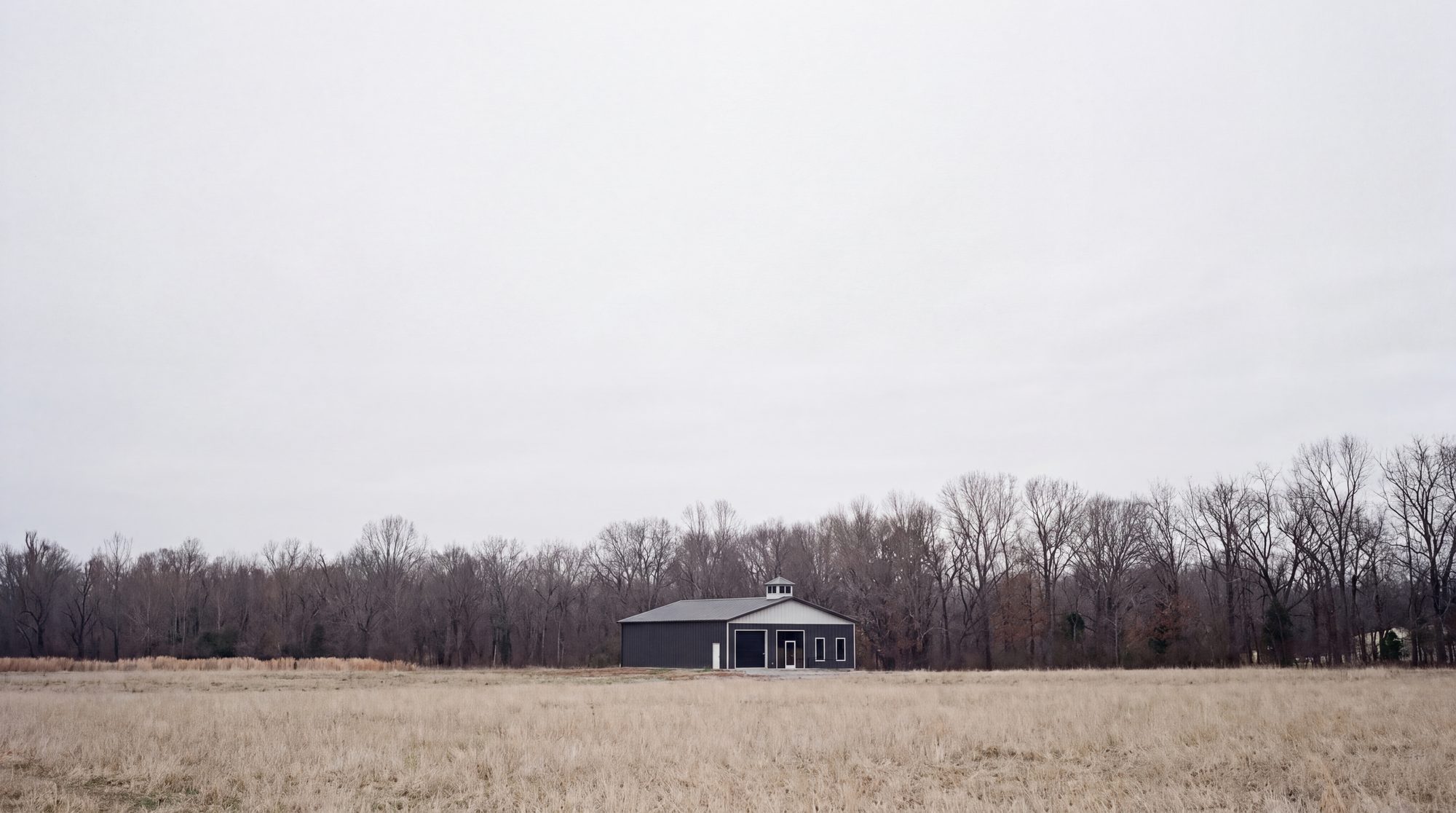 The building small across a field of winter grass